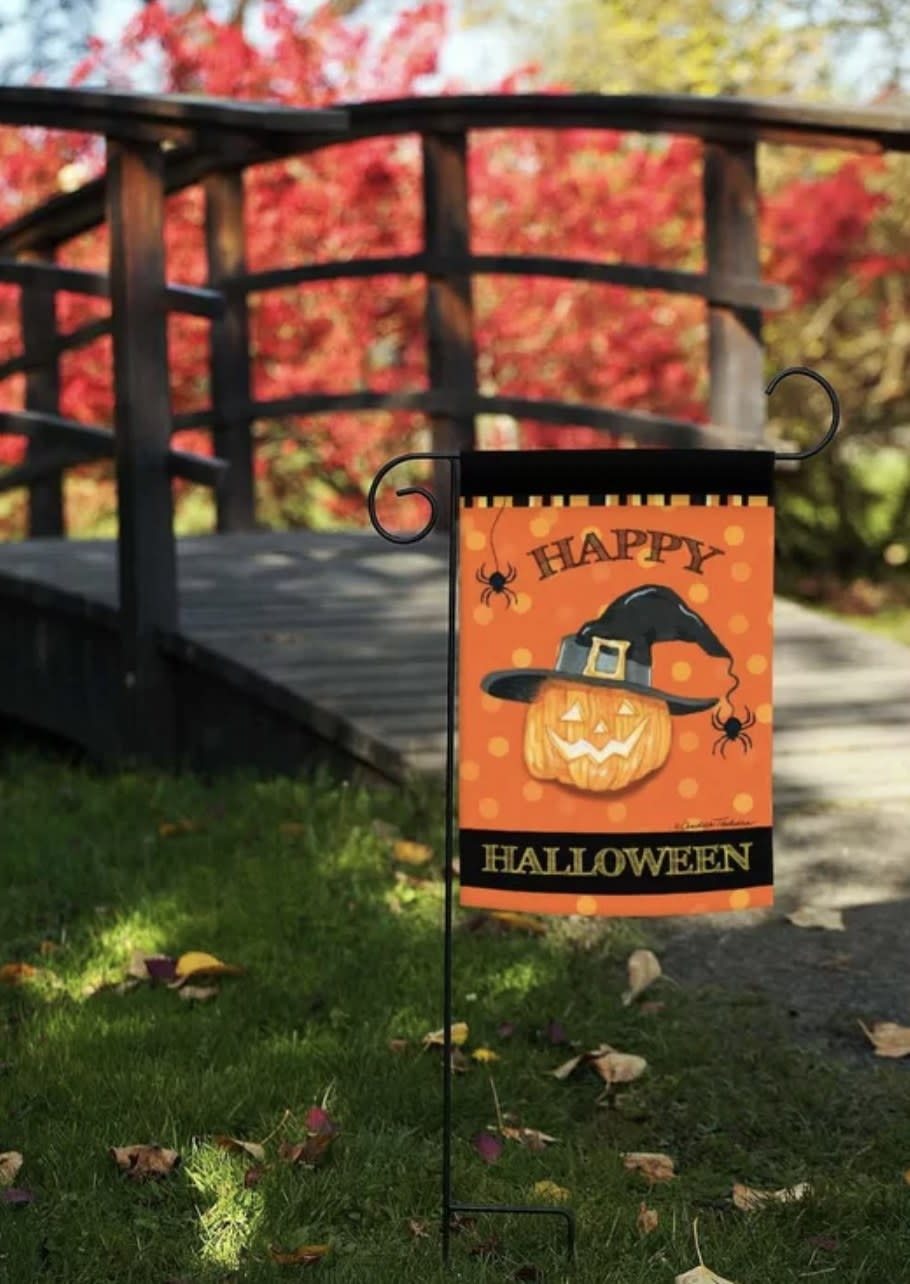 The orange flag with black borders says "HAPPY HALLOWEEN" and has a jack-o-lantern wearing a witch hat and with spiders
