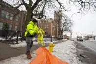 Thomas McGee, an employee with the City of Rochester, cleans up police tape outside of the Main Street Armory on Monday, March 6, 2023, in Rochester, N.Y. (AP Photo/Lauren Petracca)