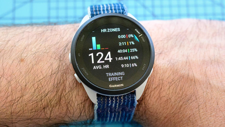 The Garmin Forerunner 165 GPS watch on a user's wrist with a blue woven band attached