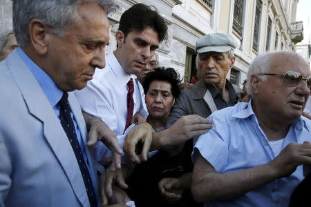 Pensioners are given priority tickets by a National Bank branch manager (L), as they wait to receive part of their pensions in Athens, Greece, July 1, 2015. REUTERS/Alkis Konstantinidis