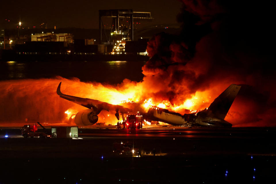 Firefighters work at Haneda International Airport after Japan Airlines' A350 airplane caught on fire, in Tokyo, Japan January 2, 2024. REUTERS/Issei Kato