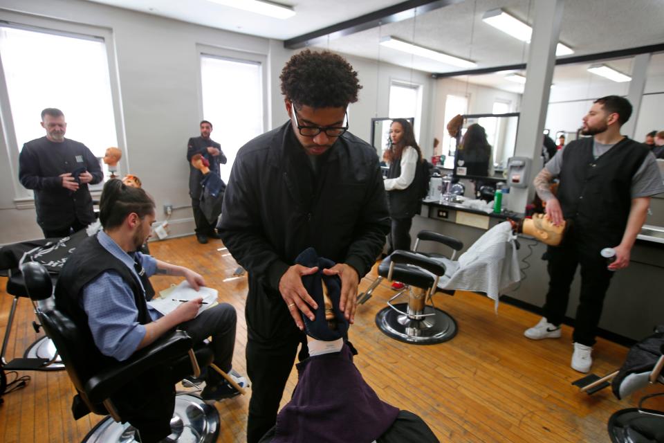 Helder Pereira places a towel on the dummy he will practice his shaving skills with at the Rob Roy Academy in Fall River.