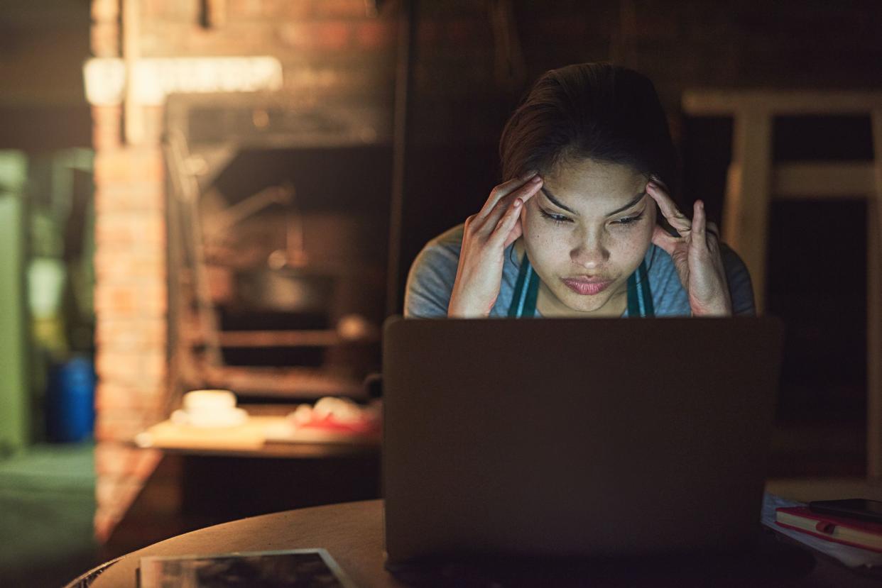 Stressed woman working on laptop at night