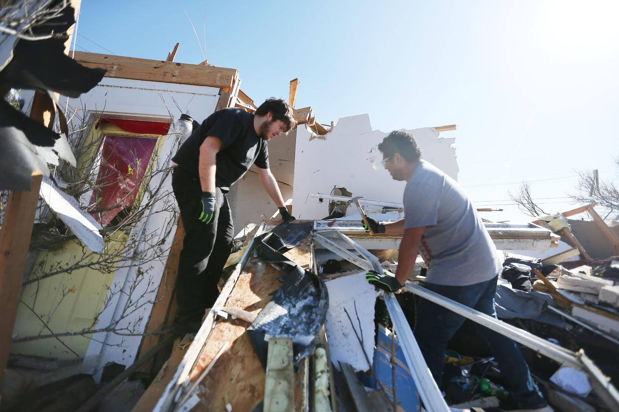 Cameron Ingram and Joshua Reyes clean up debris Tuesday in Round Rock after a tornado ripped through their home Monday night.