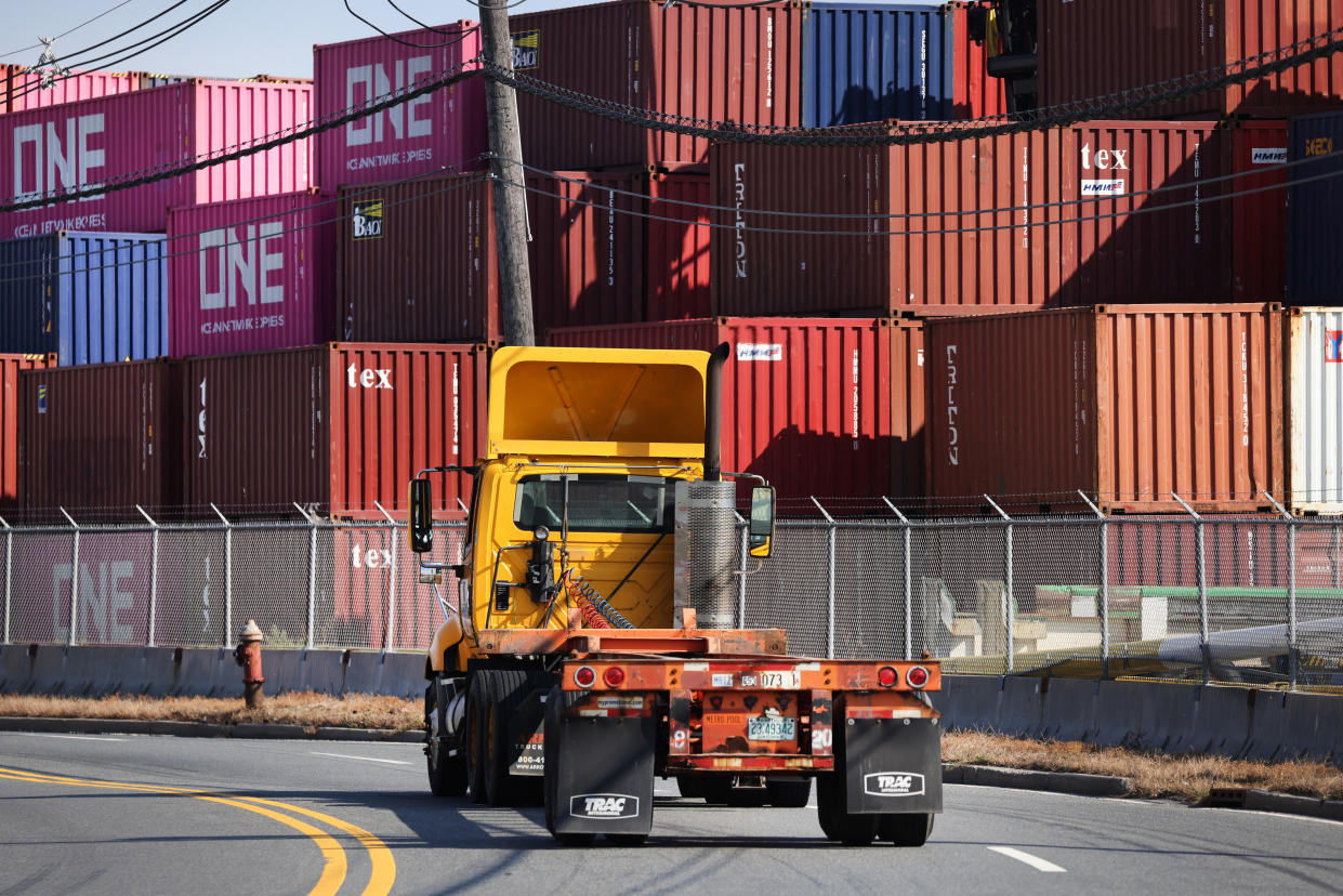 Trucks move past cargo containers at a Bayonne port on October 15, 2021 in Bayonne, New Jersey. (Photo by Spencer Platt/Getty Images)