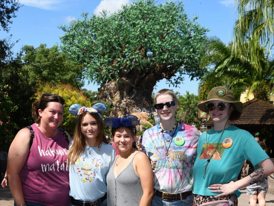 people posing for a photo in front of the tree of life in animal kingdom