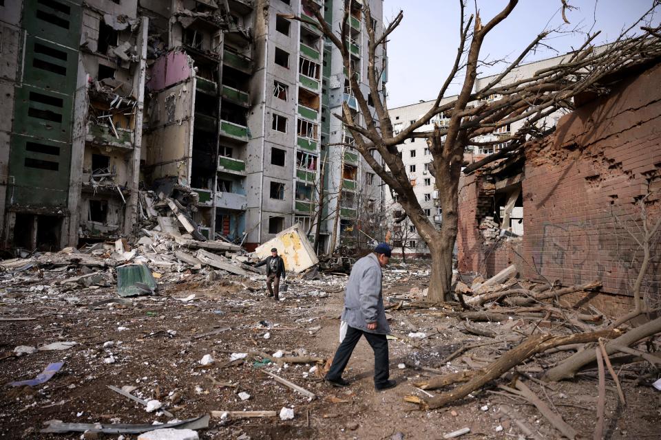 Men walk past a residential building damaged in yesterday's shelling in the city of Chernihiv on March 4, 2022. - Fourty-seven people died on March 3 when Russian forces hit residential areas, including schools and a high-rise apartment building, in the northern Ukrainian city of Chernihiv, officials said. (Photo by Dimitar DILKOFF / AFP) (Photo by DIMITAR DILKOFF/AFP via Getty Images)