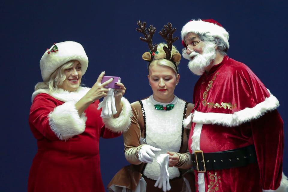 Kelly Friar, left, Megan Burnside and Mike Stone, prepare to pose for selfie while in costume during the first cast rehearsal of the Vaud-Villities upcoming Christmas show at Northland Performing Arts Center in Columbus, Ohio Nov. 9.  