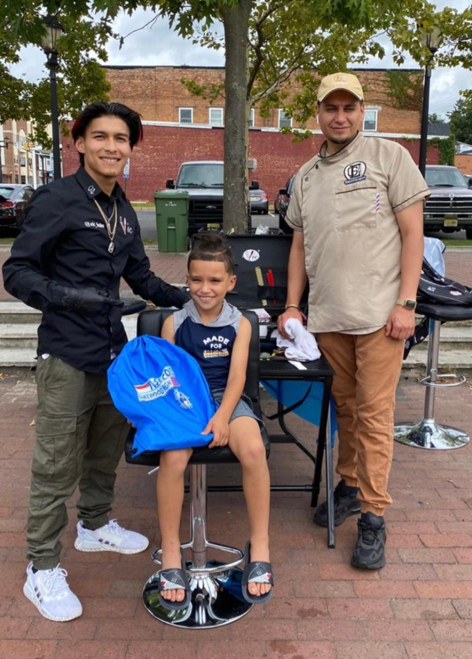 Barbers Victor Mendoza and Edgar Gallegos giving away bags with school supplies and haircuts to kids in Lakewood.