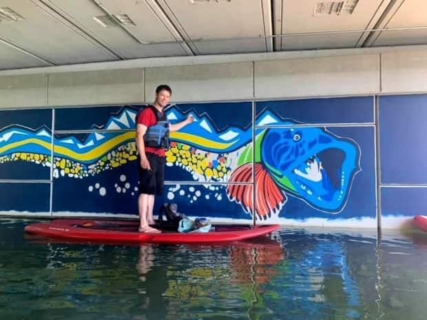 Calgary artist Brad Hays used a paddleboard and some rope when painting Bownessie in Bowness Park.  (Shawna Sharp Hays - image credit)