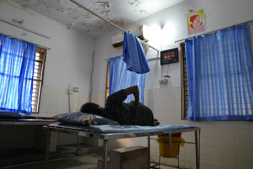 Sandhya Shivappa, 25, who is nine months pregnant, lies on her side while having labor pain as she waits to deliver at a government maternity hospital which runs on rooftop solar power, in Raichur, India, Tuesday, April 18, 2023. Government Maternity installed rooftop solar panels about a year ago and can now depend on constant electricity that keeps the lights on, patients and staff comfortable and vaccines and medicines safely refrigerated. (AP Photo/Aijaz Rahi)