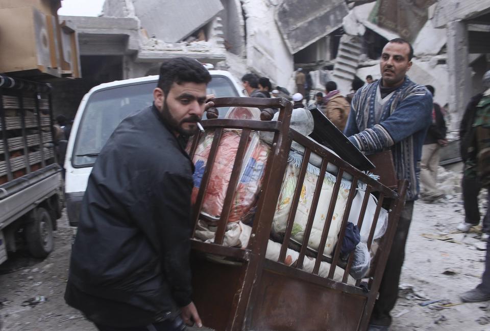 Residents collect belongings in an area damaged by what activists said was an air strike by forces loyal to Syria's President Bashar al-Assad, in Salehin neighbourhood in Aleppo January 25, 2014. REUTERS/Hosam Katan (SYRIA - Tags: CIVIL UNREST CONFLICT SOCIETY)