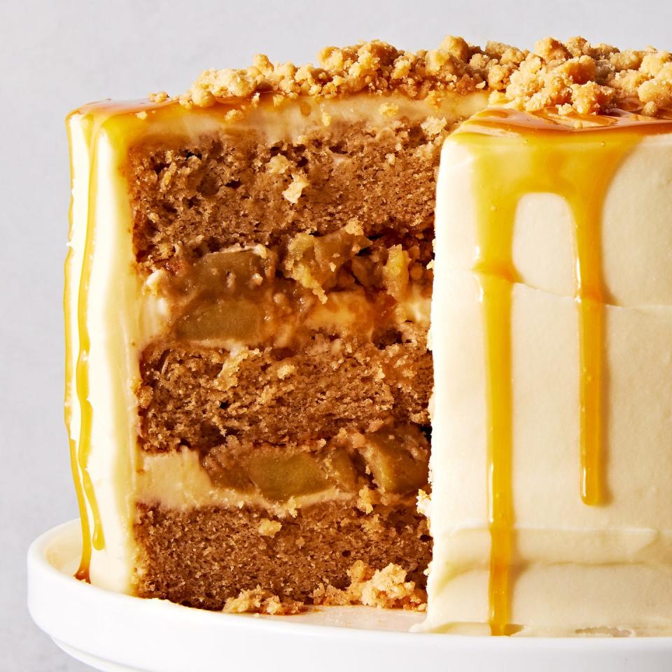 salted caramel apple crumble cake topped with caramel and crumbs on a cake stand