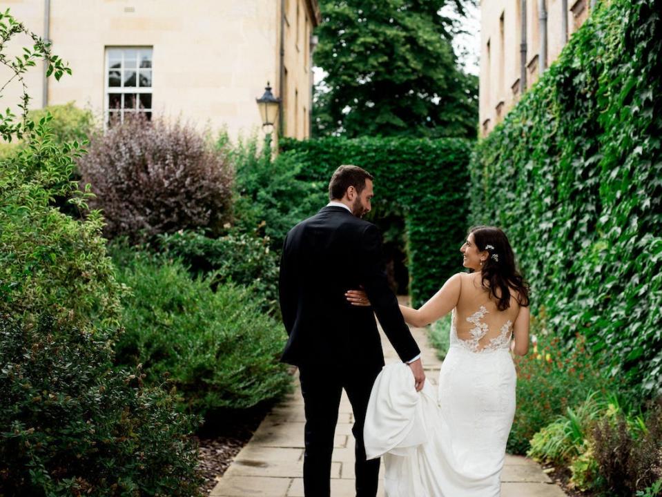 A bride and groom walk in a garden on their wedding day.