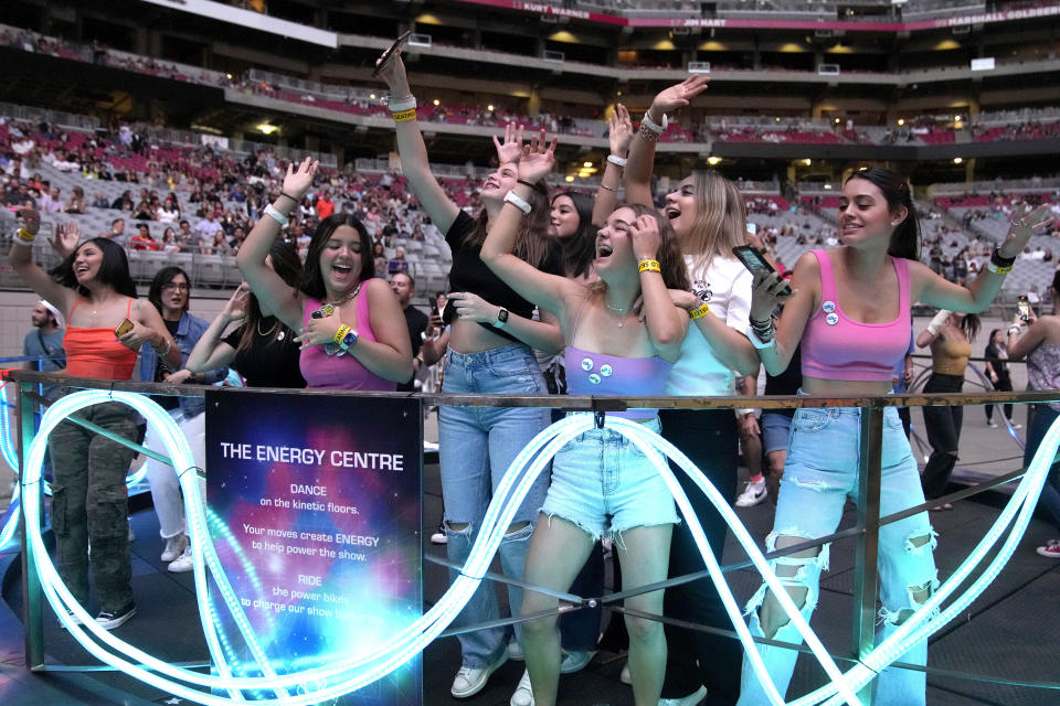 Concertgoers dance during Coldplay's Music of the Spheres world tour on Thursday, May 12, 2022, at State Farm Stadium in Glendale, Ariz. The band has included energy-storing stationary bikes to their latest world tour, encouraging fans to help power the show as part of a push to make the tour more environmentally friendly. (Photo by Rick Scuteri/Invision/AP)