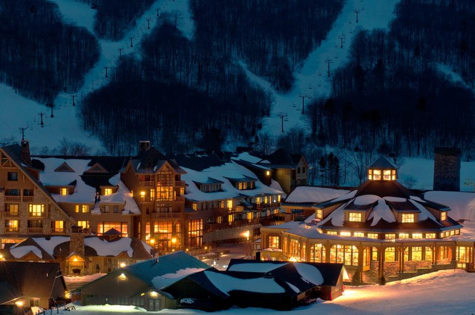 Stowe Mountain Lodge at the base of Spruce Peak glows in the early morning light against the backdrop of the FourRunner Quad lift on Mount. Mansfield as operations begin on a typical day.