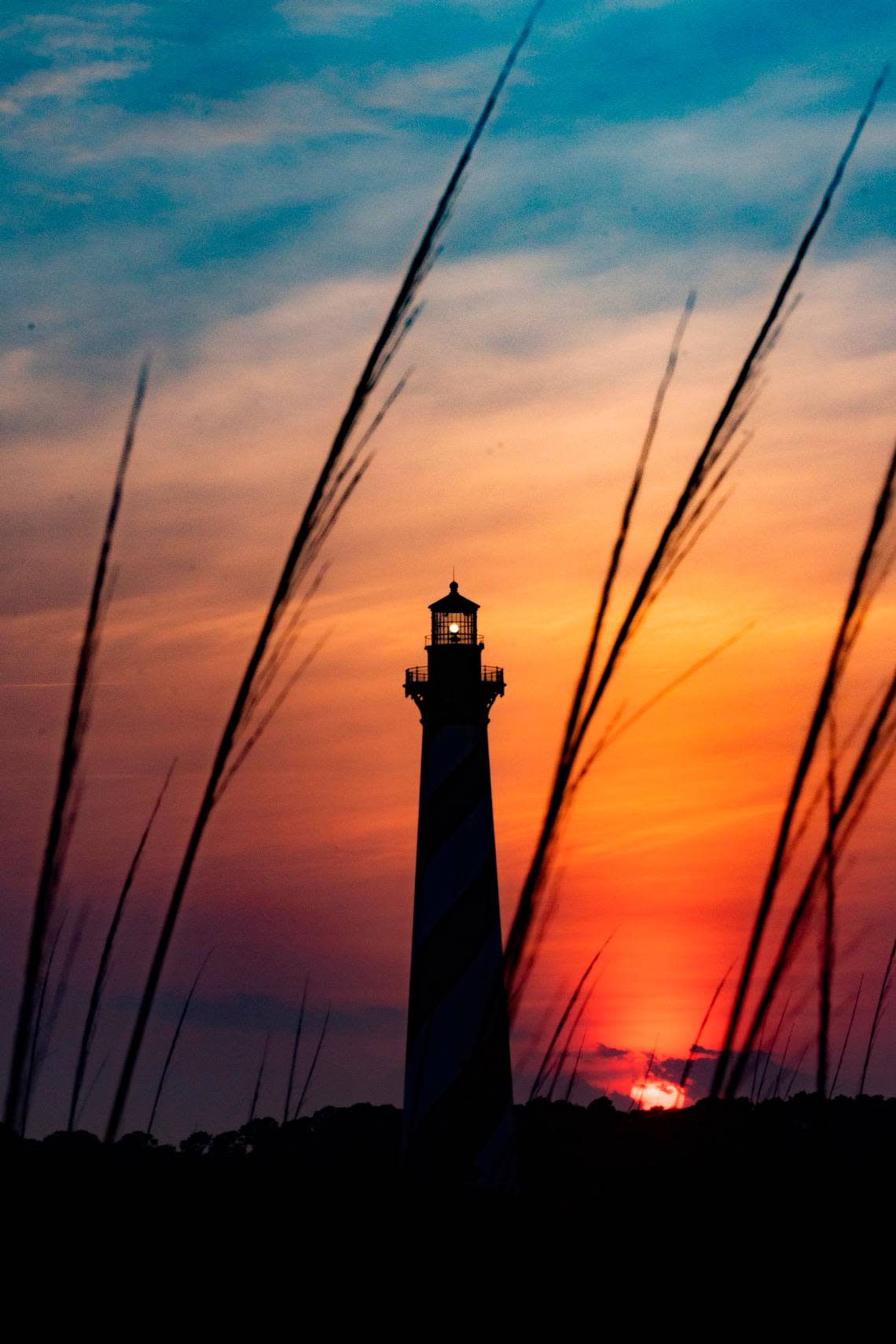 The sun sets behind the Cape Hatteras Light Station in Buxton Thursday, May 19, 2022.