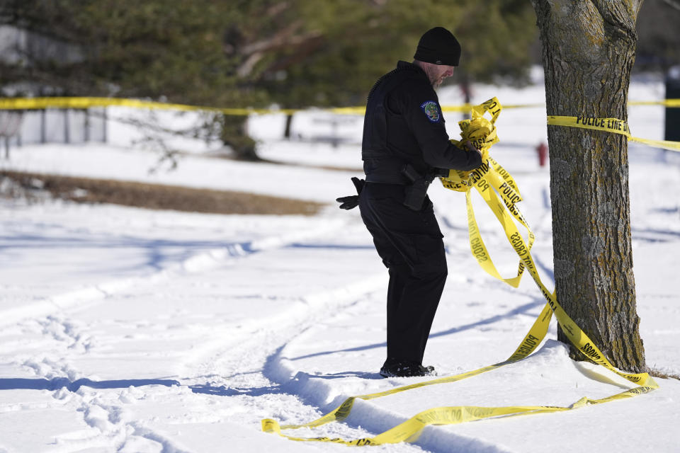 A police officer removes tape near the scene where two police officers and a first responder were shot and killed, Sunday, Feb. 18, 2024, in Burnsville, Minn. (AP Photo/Abbie Parr)