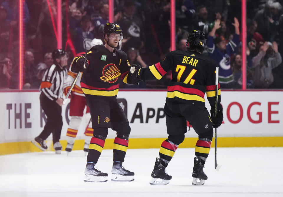 Vancouver Canucks' Elias Pettersson, left, and Ethan Bear celebrate Pettersson's shorthanded goal against the Calgary Flames during the first period of an NHL hockey game Saturday, April 8, 2023, in Vancouver, British Columbia. (Darryl Dyck/The Canadian Press via AP)