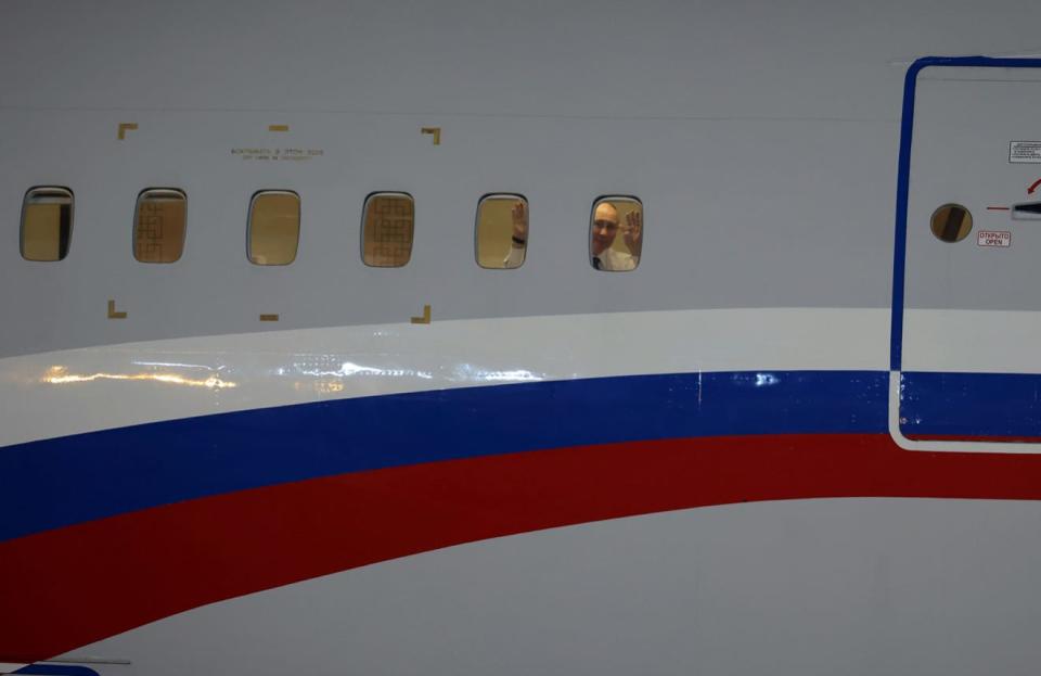 Vladimir Putin waves to Kim Jong Un and his entourage from a plane window.