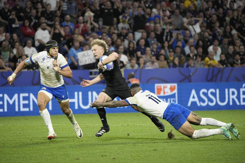 New Zealand's Damian McKenzie, center, evades Italy's Juan Ignacio Brex, left, and Italy's Montanna Ioane during the Rugby World Cup Pool A match between New Zealand and Italy at the OL Stadium in Lyon, France, Friday, Sept. 29, 2023. (AP Photo/Laurent Cipriani)