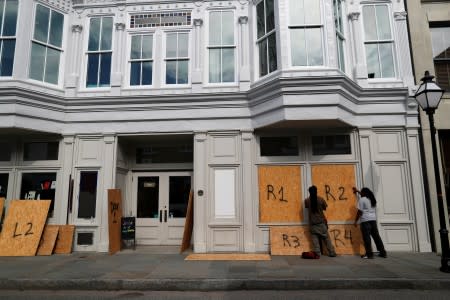 Workers place hurricane shutters on a business on King Street ahead of the arrival of Hurricane Dorian in Charleston