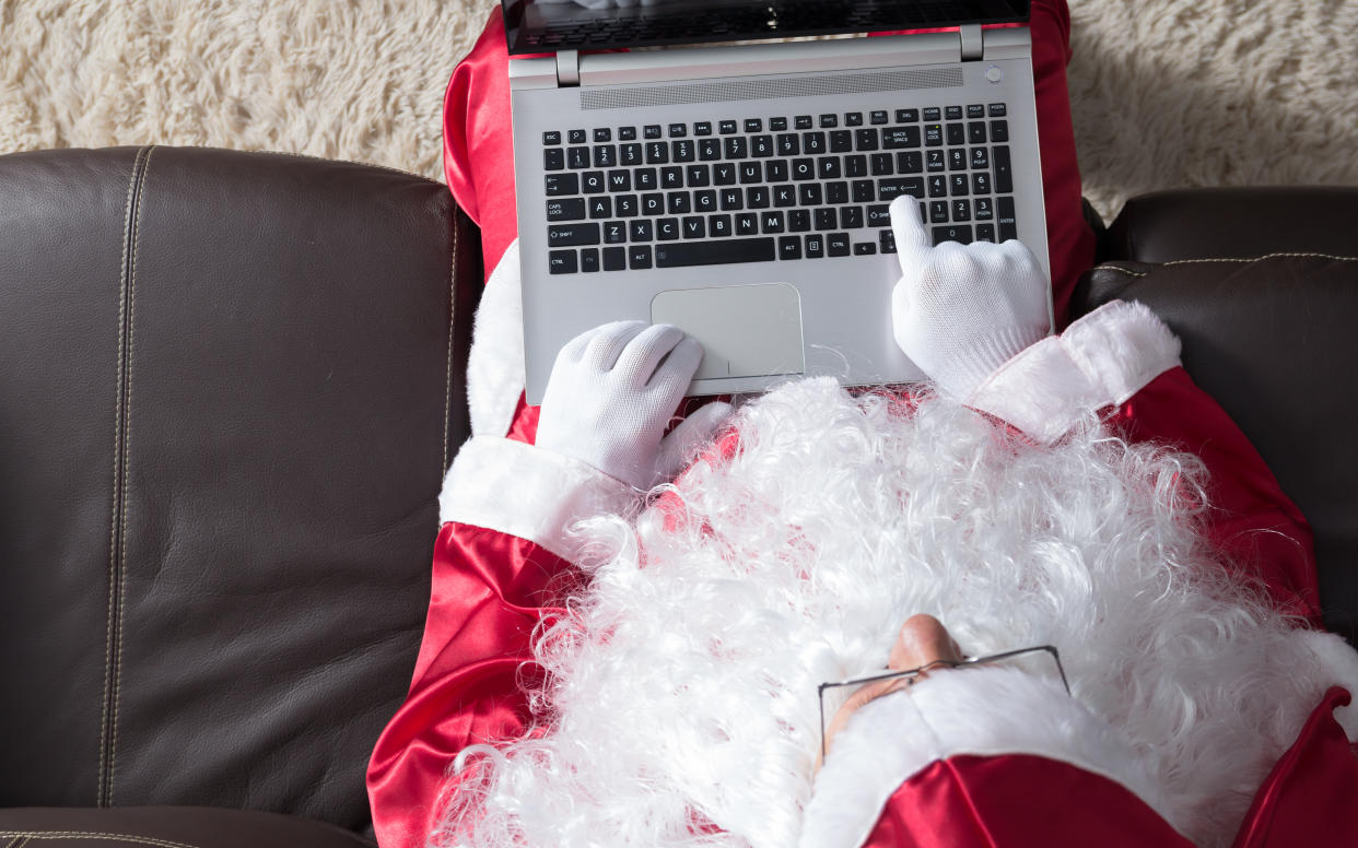 High Angle View Of Person Dressed In Santa Claus Costume Using Laptop While Sitting On Sofa