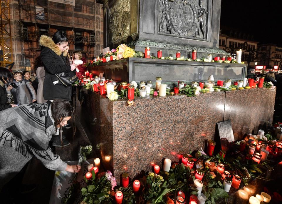 People place candles and flowers at a monument on the market place during a mourning for the victims of the shooting in Hanau, Germany, Thursday, Feb. 20, 2020. A 43-year-old German man shot and killed nine people at several locations in a Frankfurt suburb overnight in attacks that appear to have been motivated by far-right beliefs, officials said Thursday. (AP Photo/Martin Meissner)