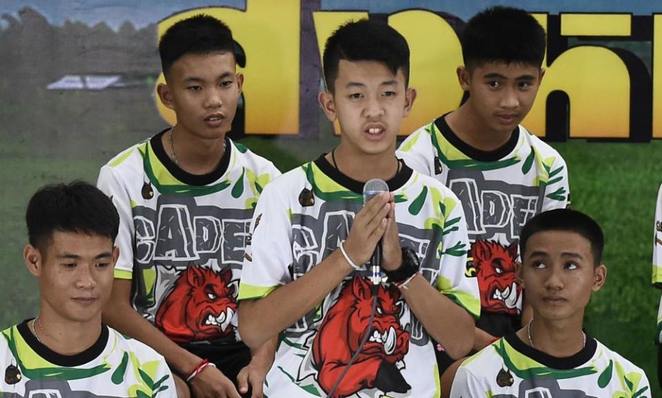 One of the twelve boys dramatically rescued from deep inside a Thai cave after being trapped for more than a fortnight, speaks during a press conference in Chiang Rai on July 18, 2018, following their discharge from the hospital while coach Ekkapol Chantawong (front-L) and Adul Sam-on (front-R) looks on. 