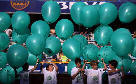 Children hold green balloons and wear t-shirts with the shield of Brazilian soccer team Chapecoense before the Argentine First Division soccer match between Boca Juniors and Racing Club to pay tribute to the victims of the plane crash in Colombia at La Bombonera stadium in Buenos Aires, Argentina, December 4, 2016. REUTERS/Marcos Brindicci