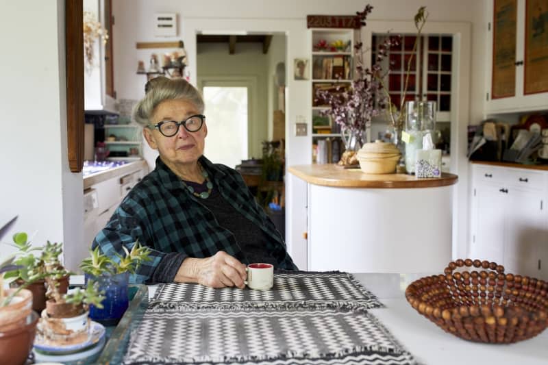 Joan sits at her kitchen table drinking from a small tea cup.