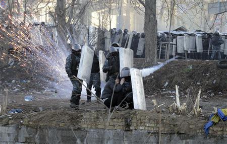 Riot police officers and a woman take cover behind shields during clashes between anti-government protesters with police in Kiev, February 18, 2014. REUTERS/Maks Levin