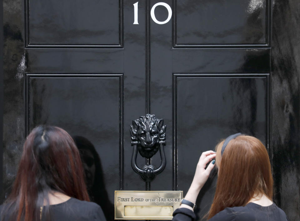 People wait at the entrance of 10 Downing Street in London, Wednesday, Aug. 28, 2019. Prime Minister Johnson has written to fellow lawmakers explaining his decision to ask Queen Elizabeth II to suspend Parliament as part of the government plans before the Brexit split from Europe. (AP Photo/Frank Augstein)