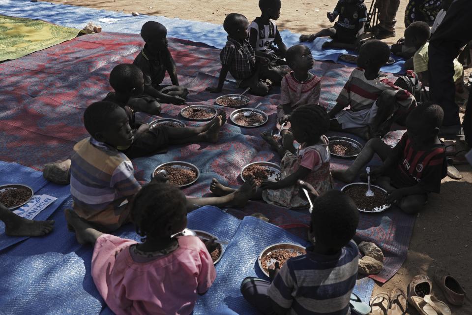 Children eat food distributed during a visit organized by The World Food Program (WFP) at Koge school, in the conflict-affected remote town of Kauda, Nuba Mountains, Sudan, Jan. 9, 2020. Sudanese Prime Minister Abdalla Hamdok, accompanied by United Nations officials, embarked on a peace mission Thursday to Kauda, a rebel stronghold, in a major step toward government efforts to end the country’s long-running civil conflicts. (AP Photo/Nariman El-Mofty)