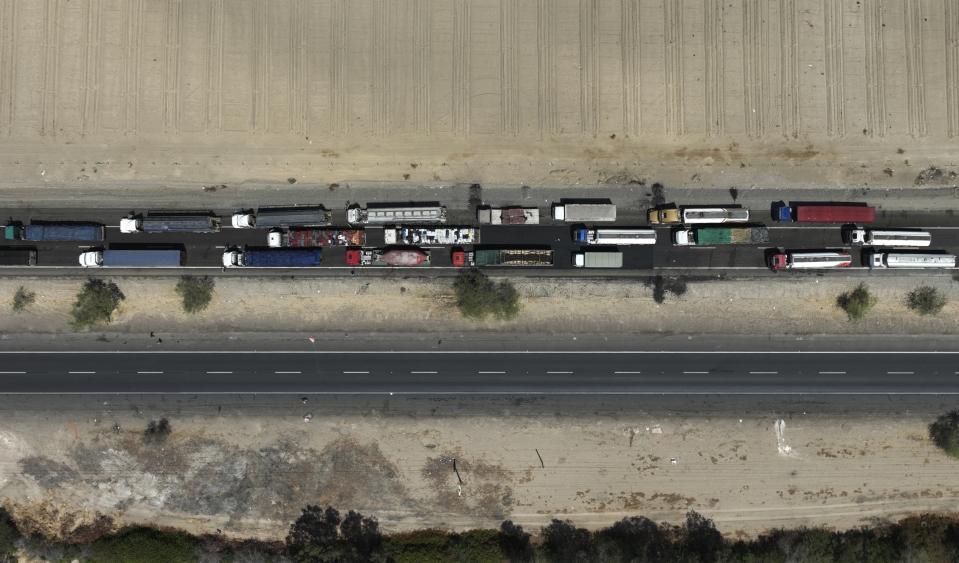 Trucks block the Pan American highway during a truckers strike in Ica, Peru, Tuesday, April 5, 2022. Peru's President Pedro Castillo imposed a curfew on the capital and the country's main port in response to sometimes violent protests over rising prices of fuel and food, requiring people in Lima and Callao to mostly stay in their homes all of Tuesday. (AP Photo/Guadalupe Pardo)