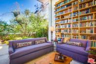 <p>The open-concept living room is centered around an enormous custom wood bookcase, which we can only assume will be used to store her copies of George R.R. Martin’s “Song of Ice and Fire.” (Zillow) </p>