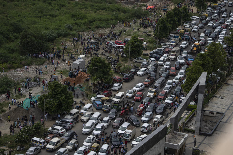 A street is blocked with vehicles as people gather to witness a controlled demolition of twin high-rise apartment towers in Noida, outskirts of New Delhi, India, Sunday, Aug. 28, 2022. The demolition was done after the country's top court declared them illegal for violating building norms. The 32-story and 29-story towers, constructed by a private builder were yet to be occupied and became India's tallest structures to be razed to the ground. (AP Photo/Altaf Qadri)