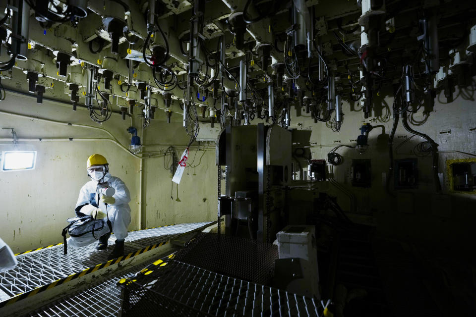 One of the Tokyo Electric Power Company Holdings (TEPCO) employees holds a radiation counter as they take AP journalists to the area under the Unit 5 reactor pressure vessel, which survived the earthquake-triggered tsunami in 2011, at the Fukushima Daiichi nuclear power plant, run by TEPCO, in Futaba town, northeastern Japan, Thursday, March 3, 2022. The government has set a decommissioning roadmap aiming for completion in 29 years. (AP Photo/Hiro Komae)