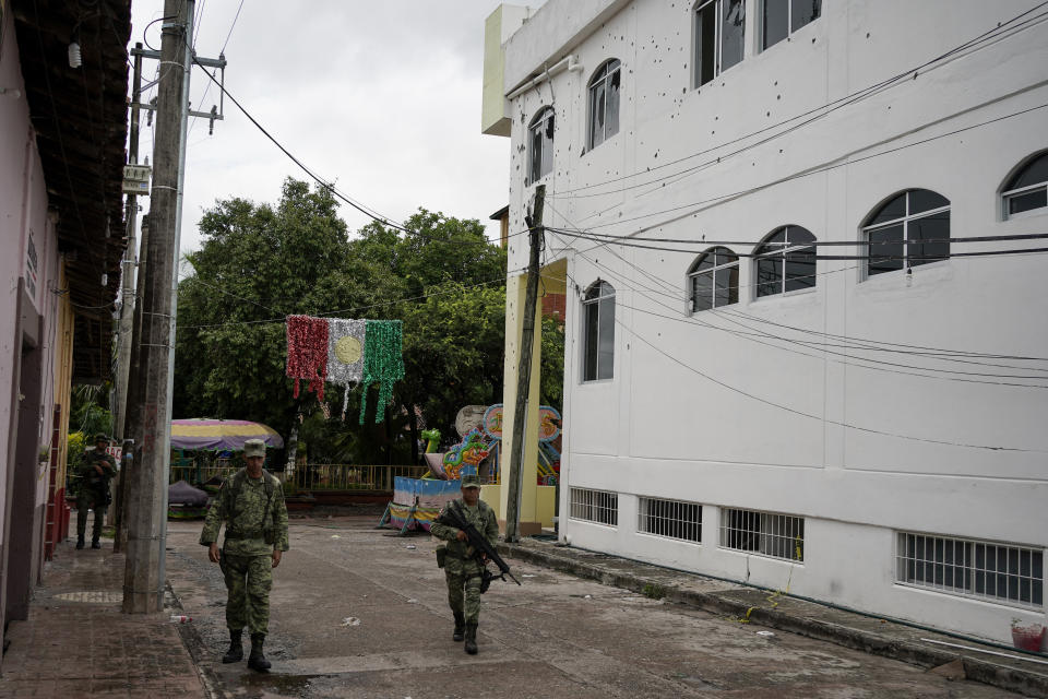 Soldiers walk past the City Hall pocketed with bullet holes the day after a mass shooting in San Miguel Totolapan, Mexico, Thursday, Oct. 6, 2022. A drug gang burst a town hall meeting and shot to death 20 people, including a mayor and his father, officials said Thursday. (AP Photo/Eduardo Verdugo)