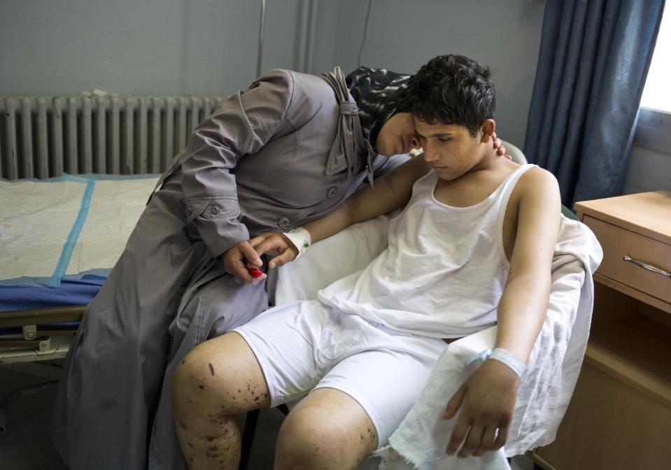 Hosen Sabah, a 16-year-old student is comforted by his mother at a hospital in Damascus, Syria, Sunday, May 4, 2014. Nosen was wounded by a mortar outside his school on April 29, 2014, while 14 other students were killed and over 80 wounded. (AP Photo/Dusan Vranic)