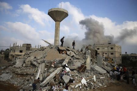 Palestinians search for victims as people gather atop the remains of a house, which witnesses said was destroyed in an Israeli air strike, in Rafah in the southern Gaza Strip July 29, 2014. REUTERS/Ibraheem Abu Mustafa