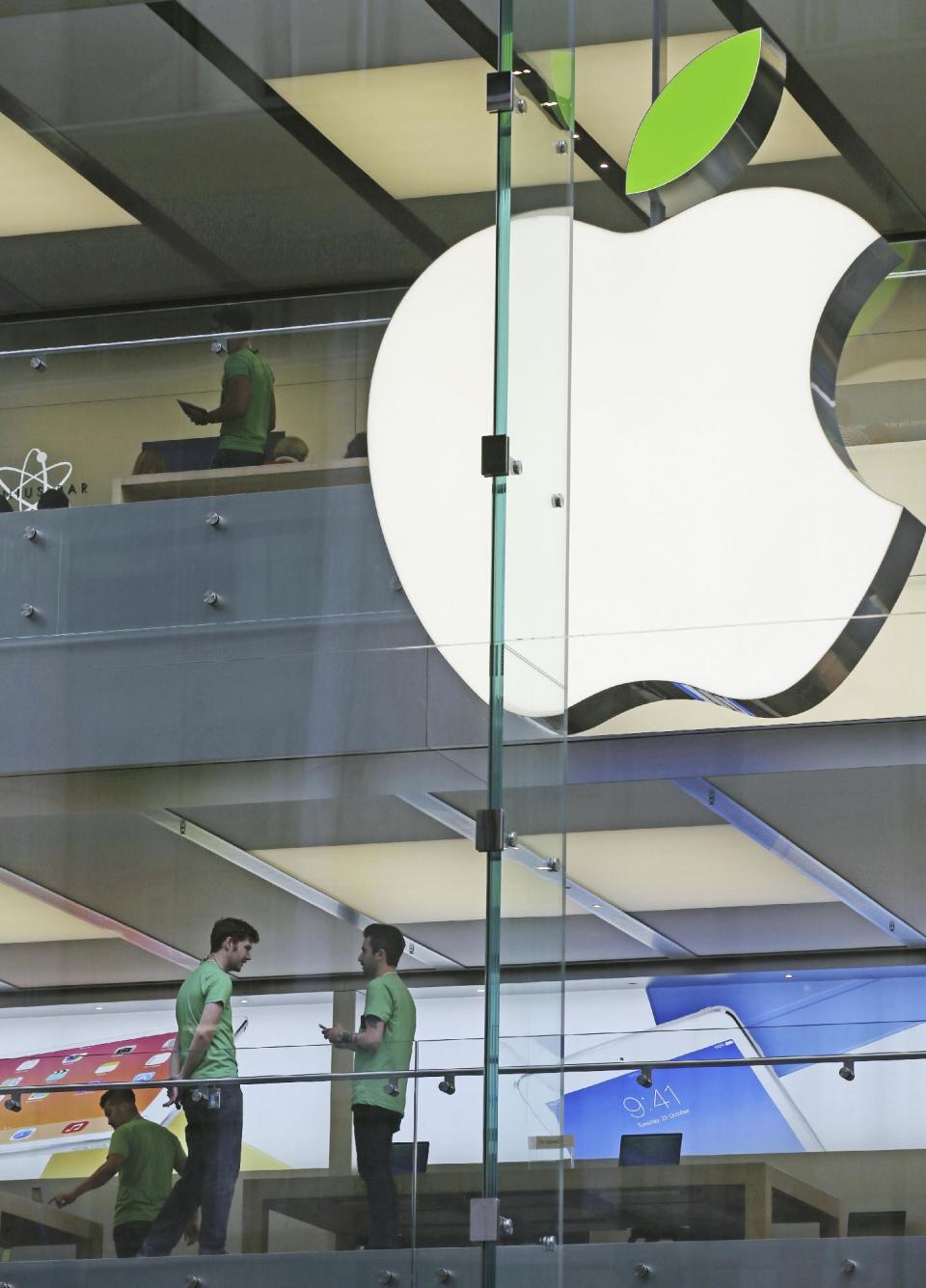 Employees wear green shirts near Apple's familiar logo displayed with a green leaf at the Apple Store timed to coincide with Tuesday's annual celebration of Earth Day in Sydney, Tuesday, April 22, 2014. Apple is offering free recycling of all its used products and vowing to power all of its stores, offices and data centers with renewable energy to reduce the pollution caused by its devices and online services. (AP Photo/Rick Rycroft)