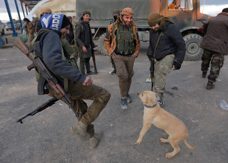 A Turkish-backed Syrian rebel plays with a dog at Manbij countryside, Syria December 28, 2018. REUTERS/Khalil Ashawi