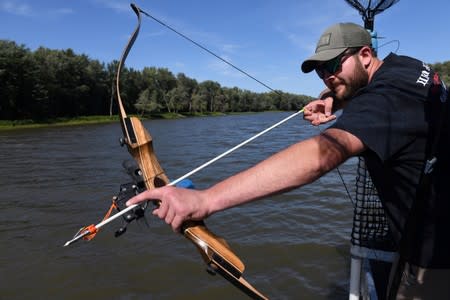 Zach VandeVusse, 23, an electrician from Hamilton Michigan, lines up a shot on Captain Nate Wallick's boat while out hunting Asian carp with bow and arrow, on the Illinois River near Lacon