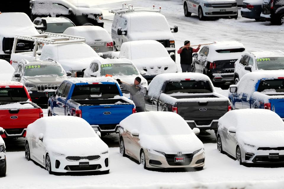 Workers at a Ford dealership clear fresh snow from vehicles in the used car lot, Tuesday, Jan. 31, 2023, in Auburn, Maine. Residents in the Northeast should enjoy a nice break from winter weather this weekend.