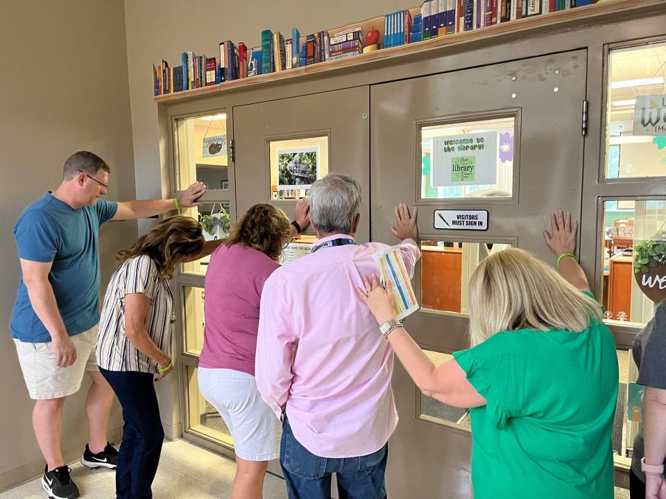 Forest High School teacher Buddy Wyckoff (center in pink shirt) prays at the door of the school’s library with members of Prayer Walk on Sunday. The Prayer Walk was part of this year’s “Go, Gather, Give” event held by Church of Hope in Ocala. Teams went to 43 Marion County Public Schools to meet a school representative for a walk around the facility while offering prayers for students, teachers and parents ahead of the upcoming school year.