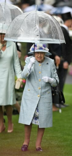 Britain's Queen Elizabeth II shelters from the rain on day two of Royal Ascot