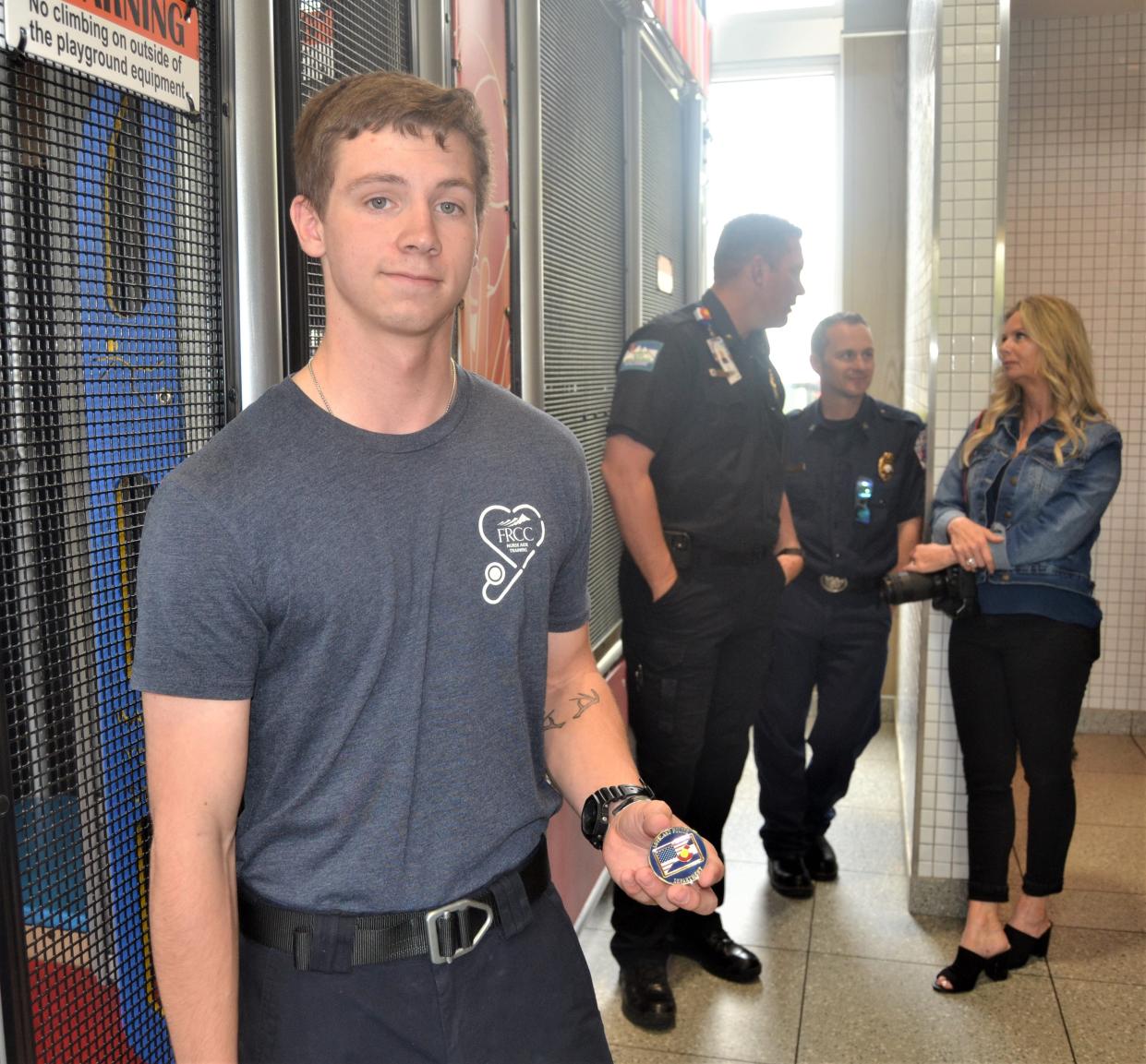 William Berglin, 18, shows off the honor coin he received from his school resource officer at Thompson Valley High School for helping saving a man's life a week earlier before a news conference May 24, 2023, at a McDonald's restaurant in Loveland, Colo.