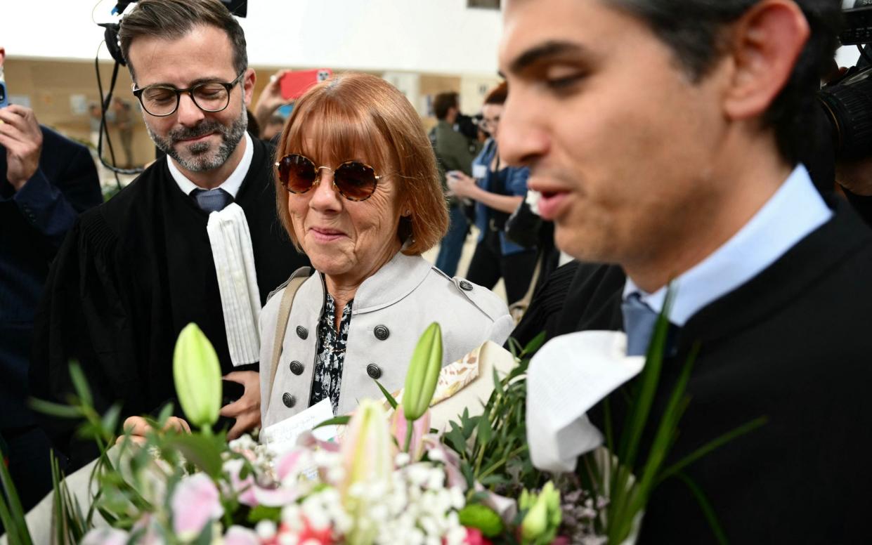 Mrs Pélicot smiles as she is given a bouquet of flowers from a member of the public