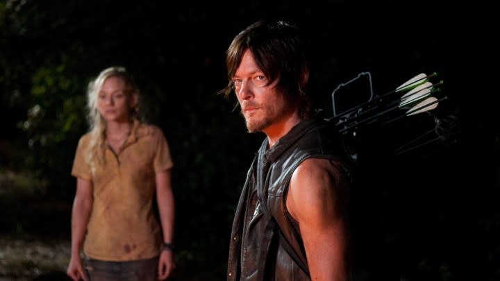 Daryl standing, looking menacing with Beth in the background in a scene from The Walking Dead.